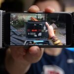 Person holding smartphone with game controller attachment